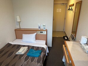 A hotel room with a bed, a bedside table, a mirror, and a door leading to a bathroom. - Hotel Big Marine Amami (Amami)