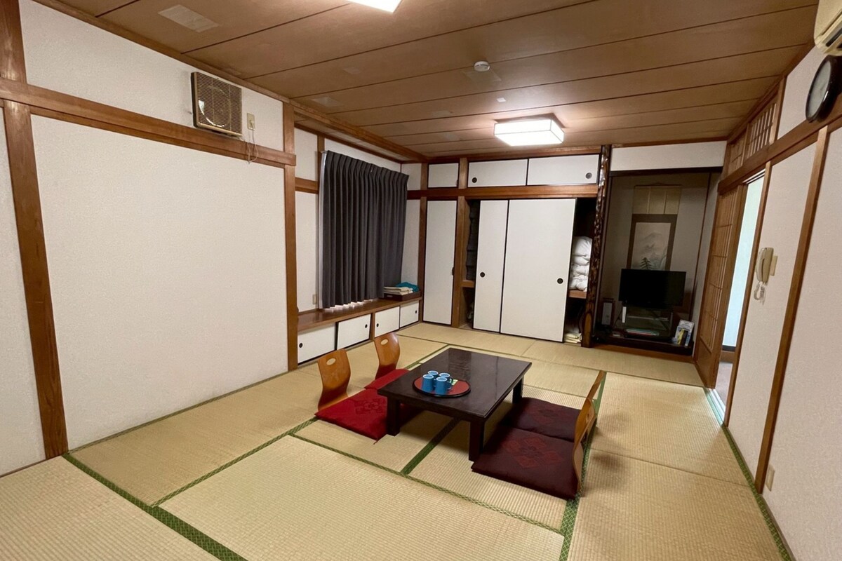 Una habitación japonesa tradicional con suelo de tatami, una mesa baja y un televisor.