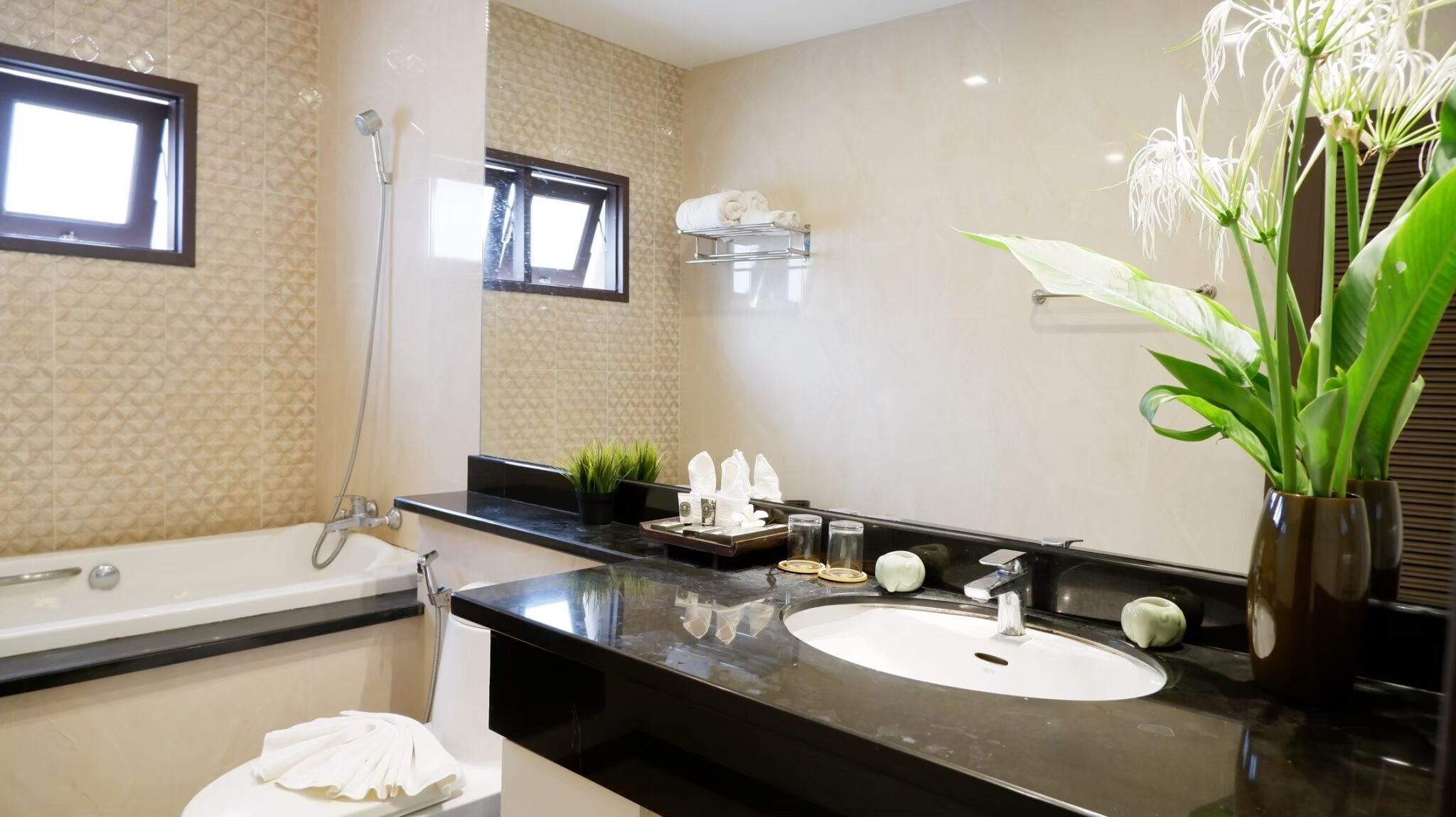 Une salle de bain moderne avec une baignoire, un lavabo, un miroir et une plante en pot.