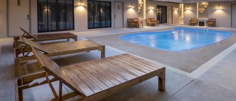 Et poolområde med træliggestole og en swimmingpool.