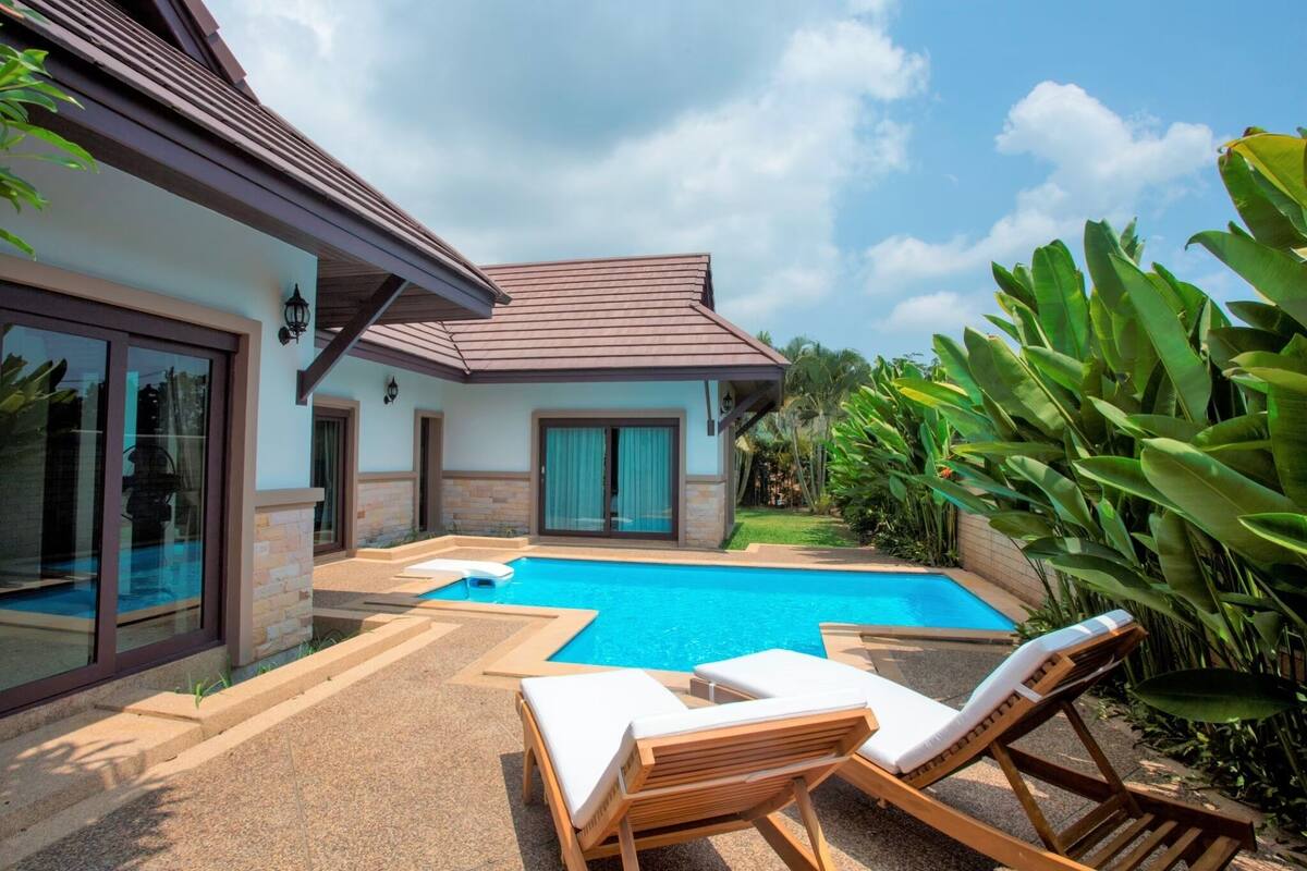 Una casa moderna con piscina, ventanas amplias y jardín.