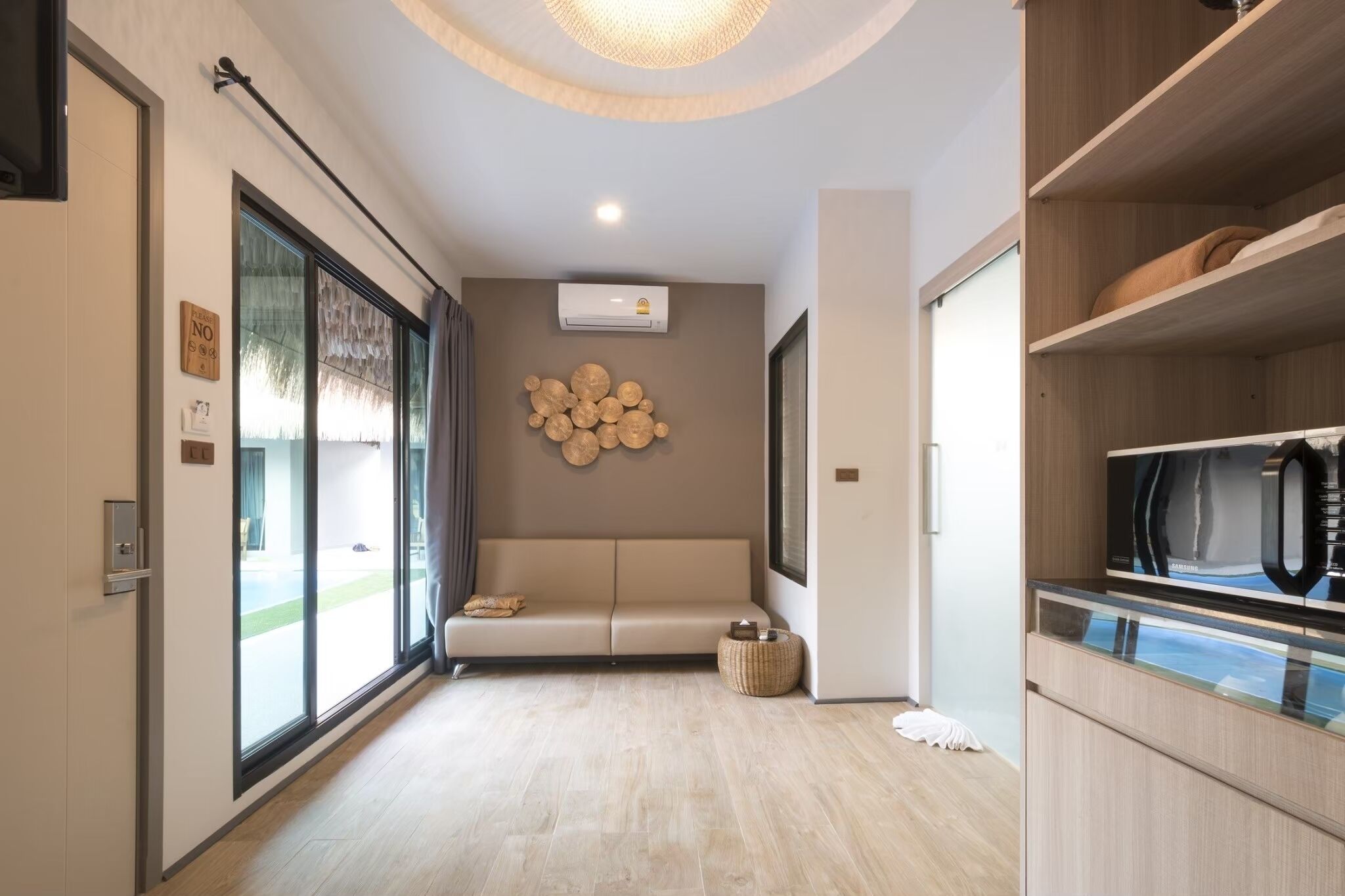 Un interno moderno con un divano, un condizionatore d'aria a parete e un angolo cottura con forno a microonde.