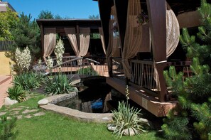 Un espace extérieur abrité, doté d’une terrasse en bois, d’un petit étang et de diverses plantes.