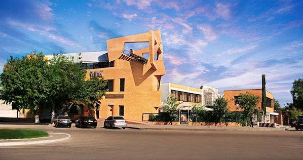 A modern hotel with a unique angular architecture, a covered outdoor area, and a parking lot with cars. - Uliss Hotel (Odesa)