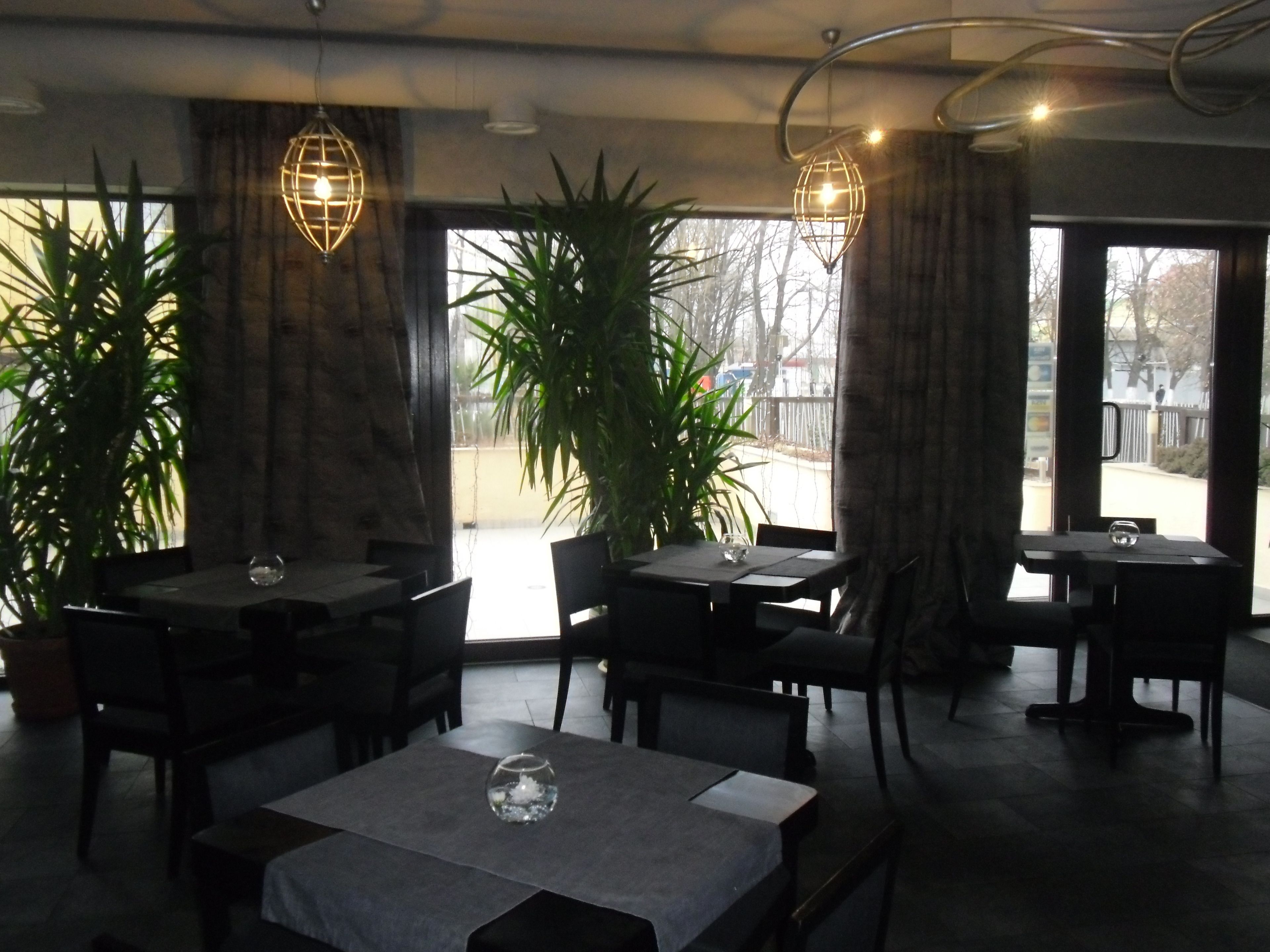 Un ristorante con tavoli e sedie, ampie finestre e lampadari.