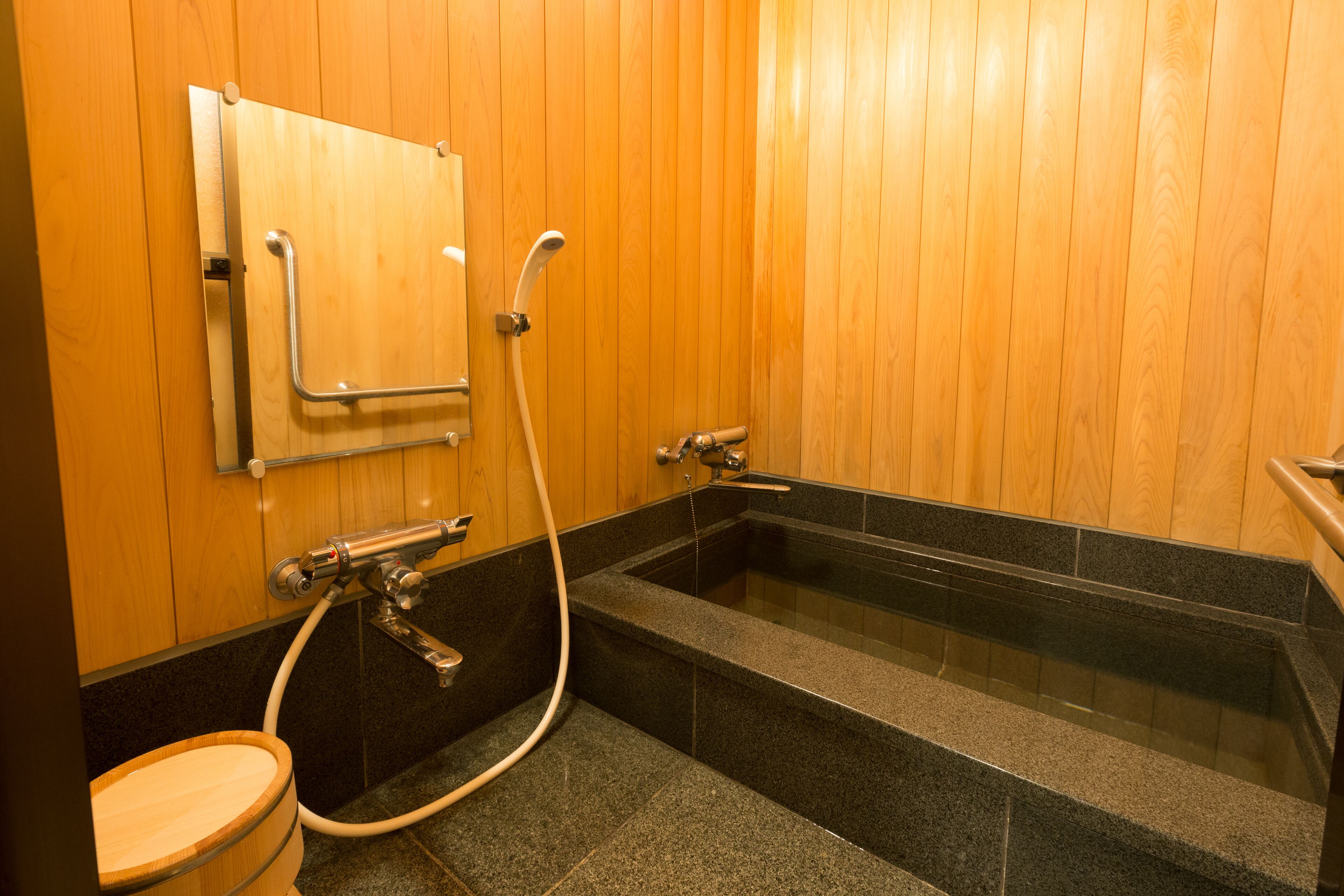 A wooden-paneled bathroom with a freestanding bathtub, a toilet, and a shower area.