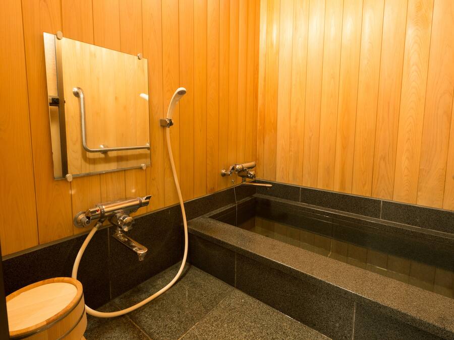 A wooden-paneled bathroom with a freestanding bathtub, a toilet, and a shower area.