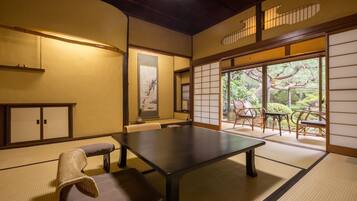 A traditional Japanese room with tatami flooring, a low table, and a seating area with cushions.
