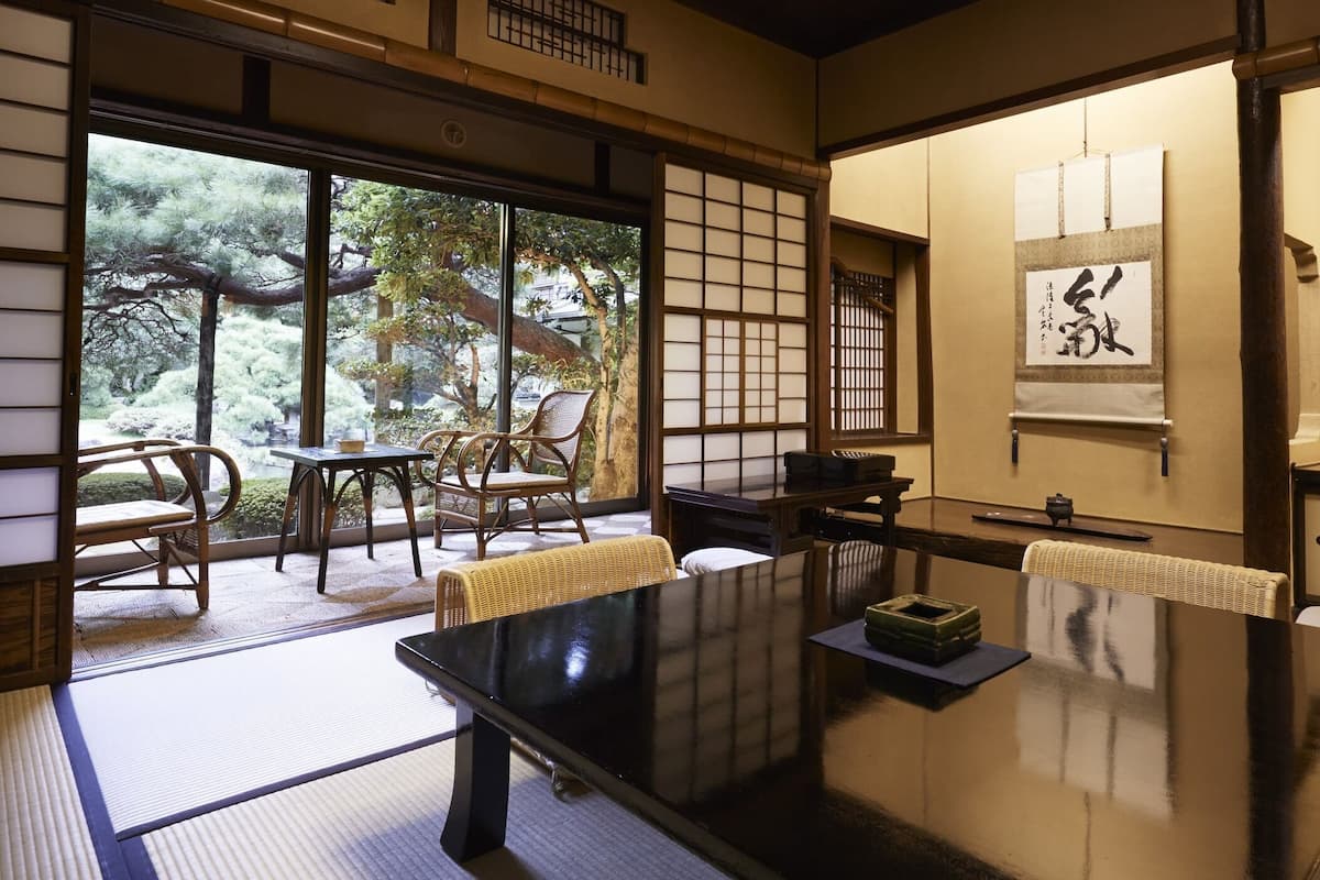 Una habitación tradicional japonesa con suelo de tatami, una mesa baja y puertas correderas.