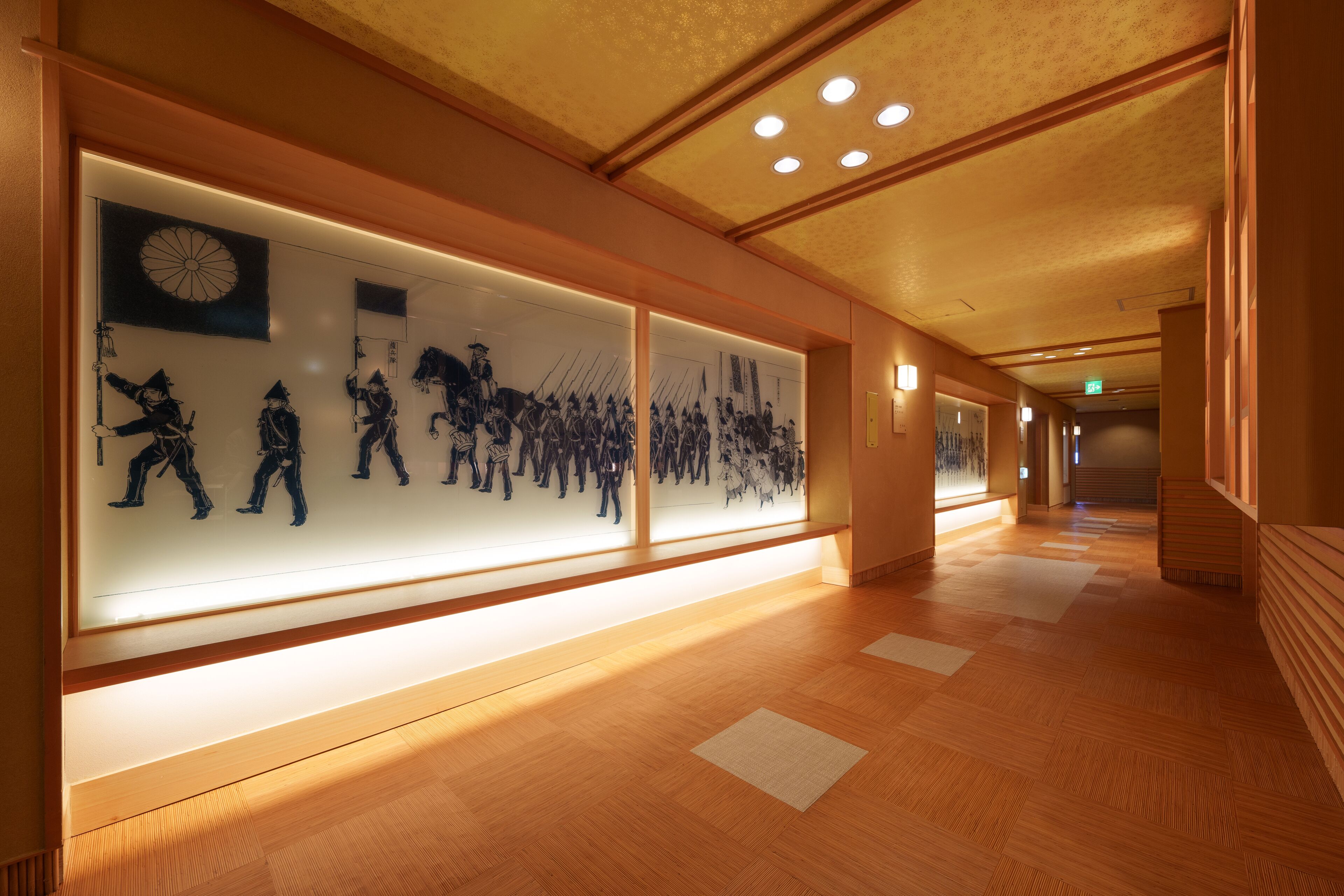 A hallway with wooden flooring and illuminated wall art depicting historical scenes.