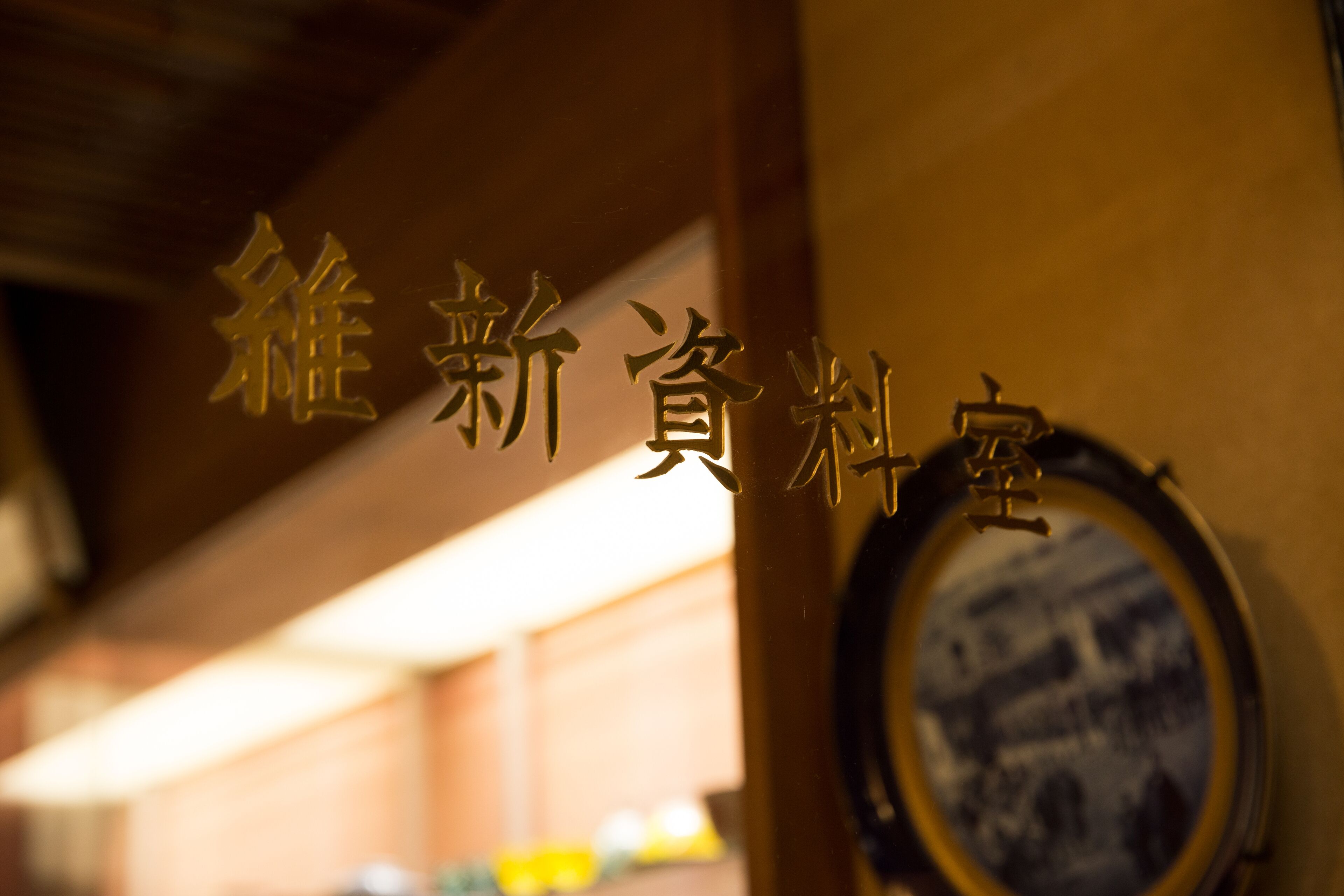 A sign with Chinese characters, a circular mirror, and a blurred background.