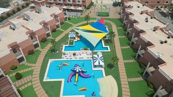 A resort with a central swimming pool, multiple balconies, and a beach area.