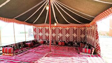 A tent with a patterned interior, multiple seating areas, and hanging lights.