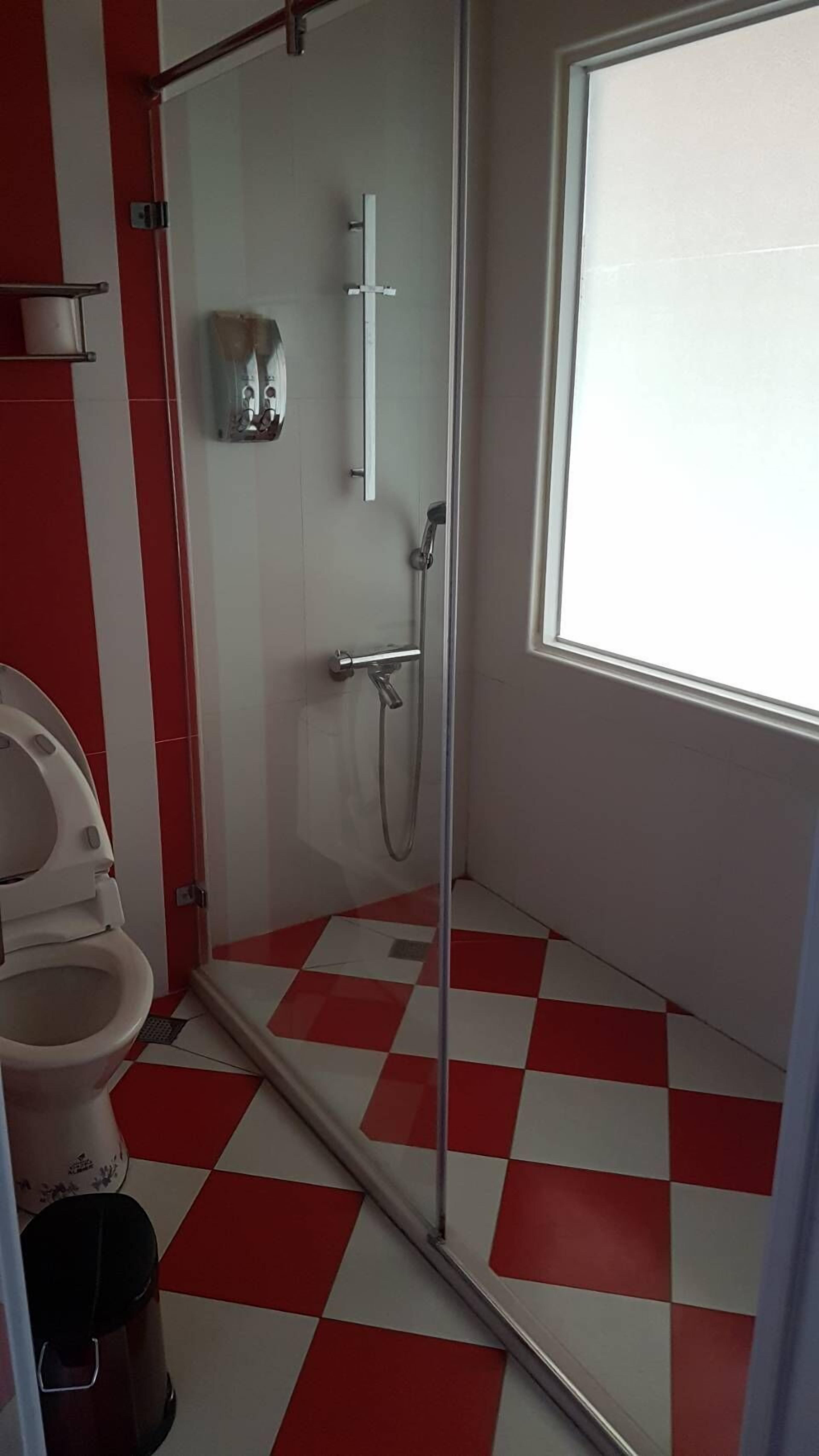 Een badkamer met een douche, toilet en een raam.
