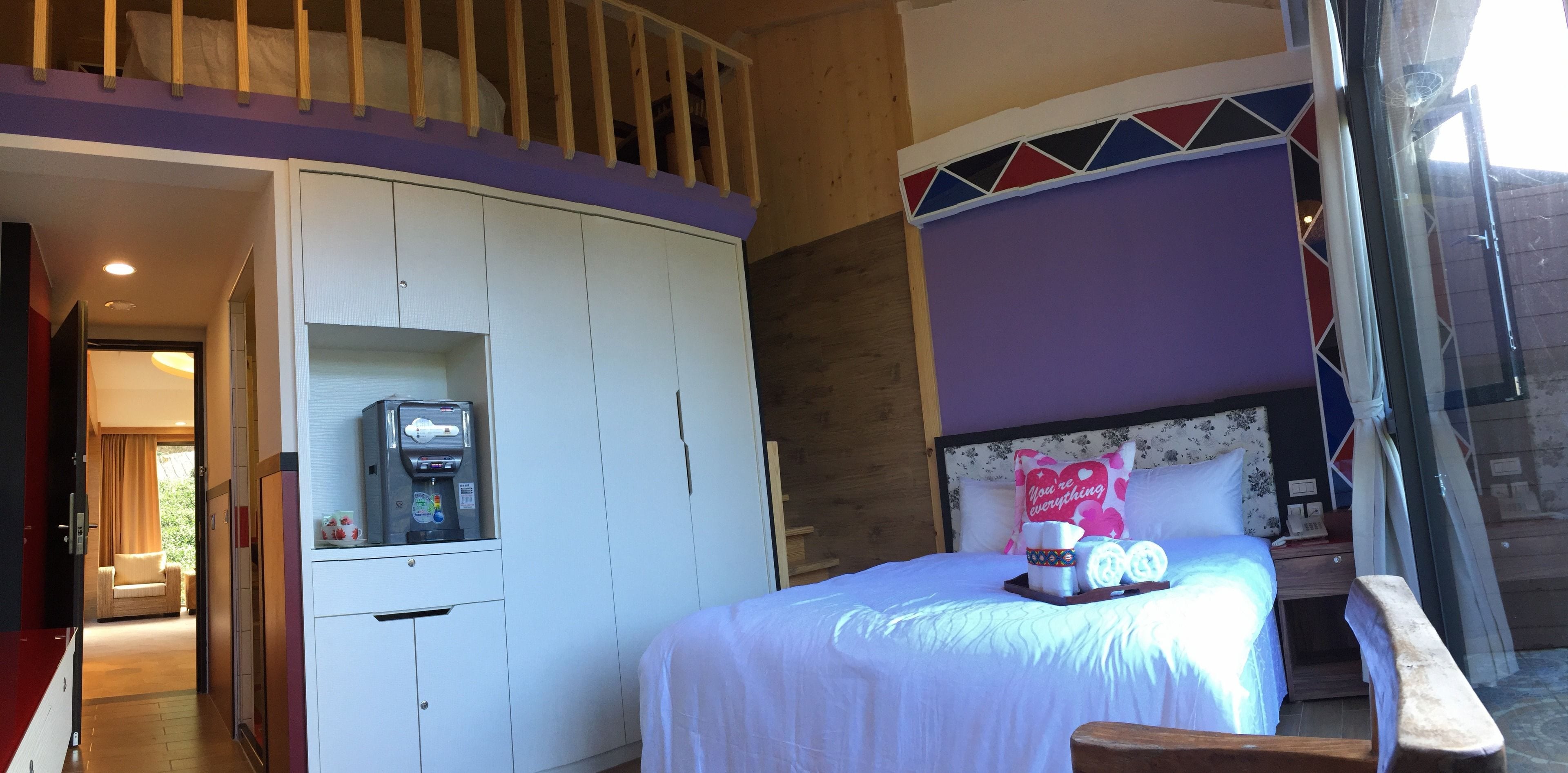 A hotel room with a bed, a coffee machine, a wardrobe, and a balcony.