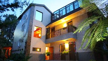 Stunning residential building with a unique architectural design, featuring a glass balcony and lush green surroundings.