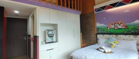 Un dormitorio con cama, armario, una pequeña kitchenette y un mural en la pared.