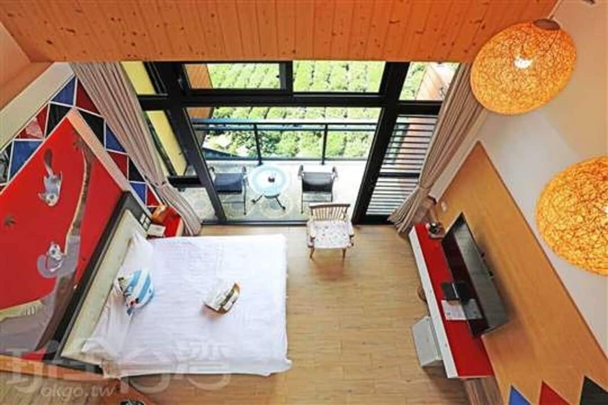 Un interior moderno con un gran ventanal, una cama, zona de comedor y televisor.