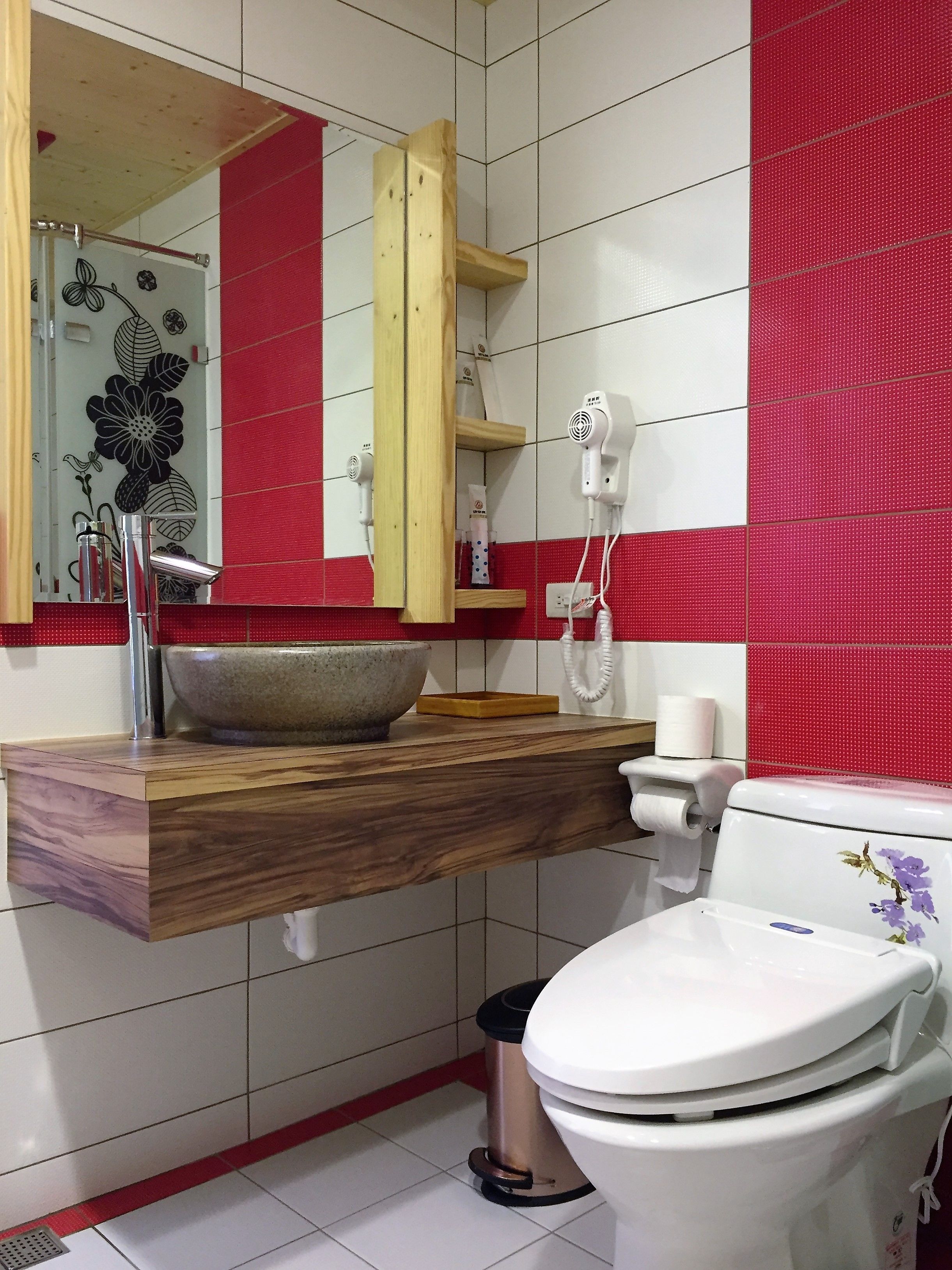 Un baño con tocador de madera, un espejo grande, inodoro blanco y una pared de acento roja.