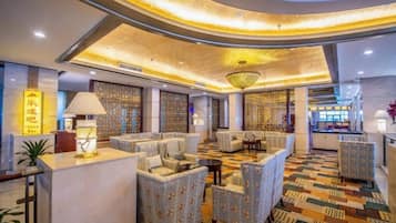 A hotel lobby with a curved ceiling, seating area, and a reception desk.