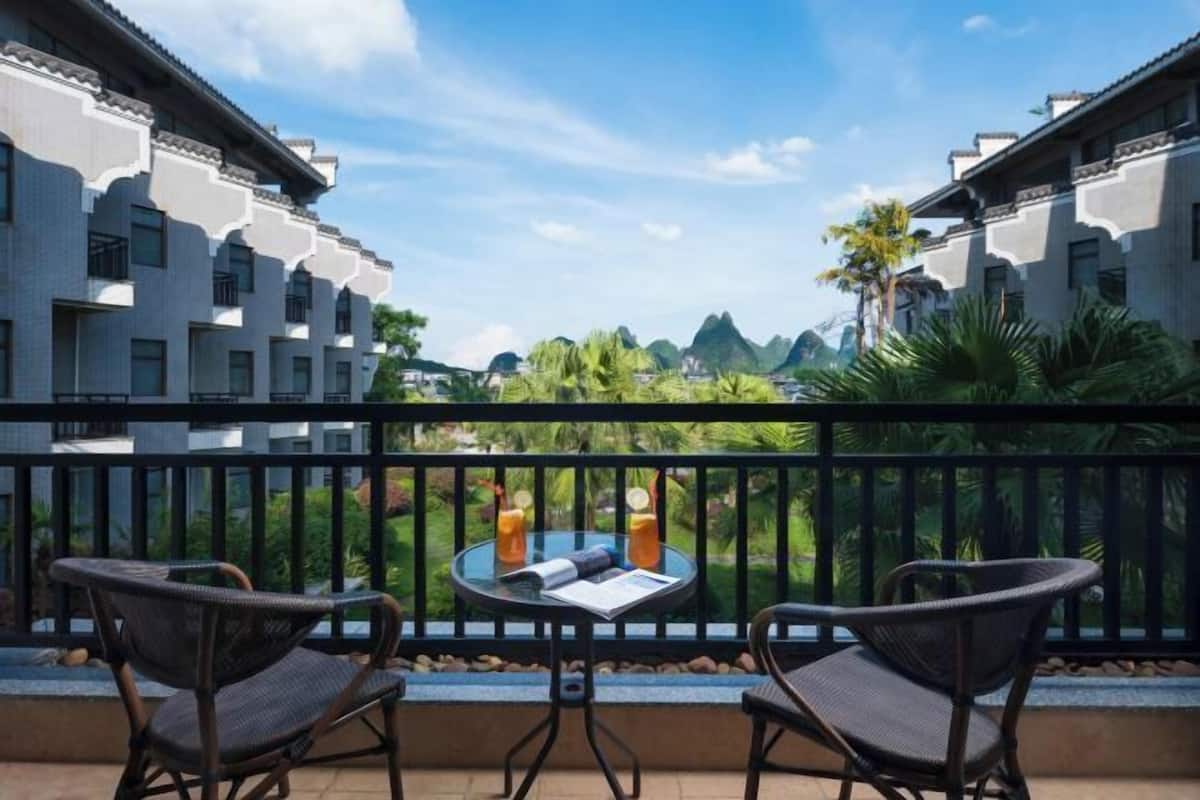 A balcony with wicker chairs, a small round table, and two drinks.