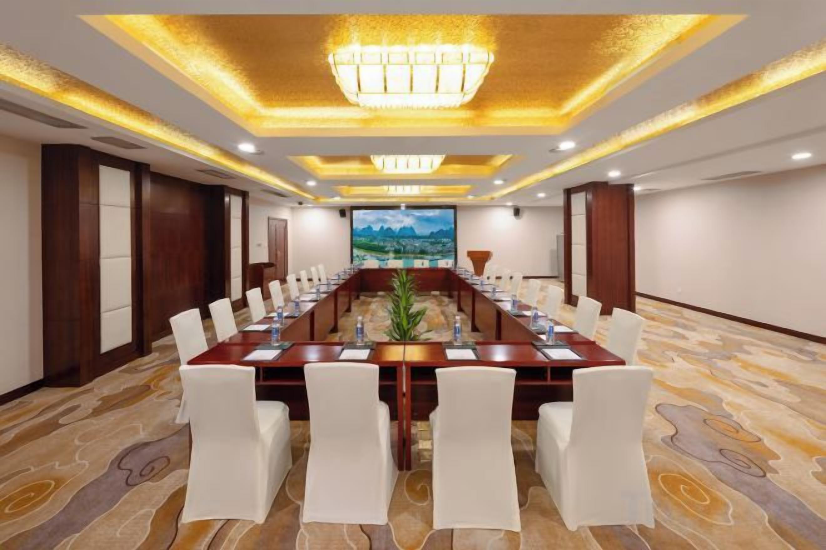 A conference room with a long table, white chairs, and a chandelier.