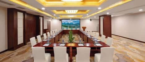 A conference room with a long table, white chairs, and a chandelier.