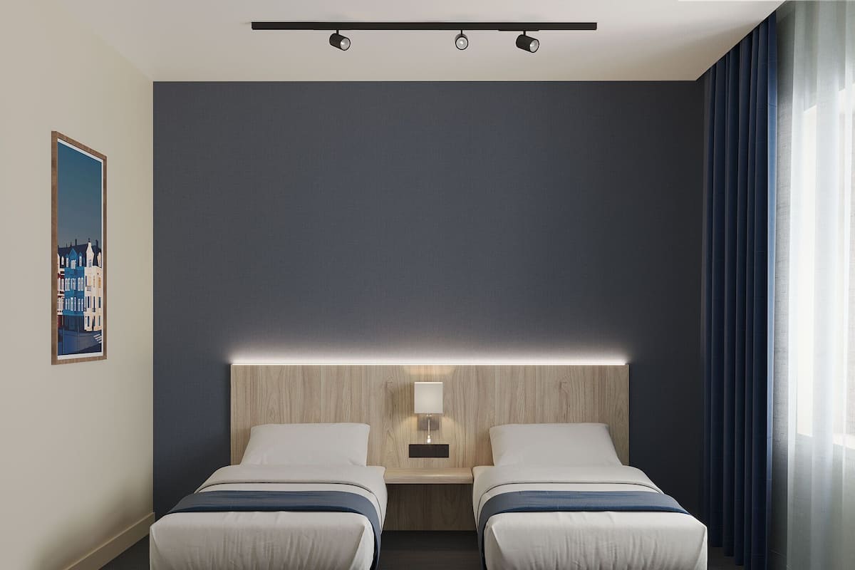 A hotel room with two beds, a headboard with integrated lighting, a nightstand, and a painting on the wall.