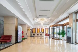 A hotel lobby with a polished floor, a reception desk, a red chair, and a chandelier. - Shanghai Yunfeng Hotel (Shanghai)