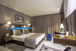 A hotel room with a bed, bedside tables, a desk, a chair, a suitcase, and a mirror. - Le Belvedere (Tunis)