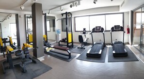 A gym with exercise equipment, treadmills, and a large window. - Le Belvedere (Tunis)