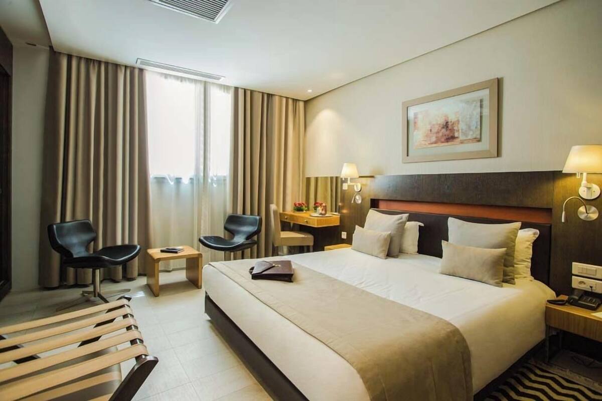 Habitació d'hotel amb un llit gran, dues cadires, un escriptori i una taula petita.