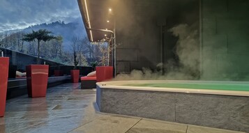 Zona de spa con hidromasaje, asientos rojos y vistas a montañas.