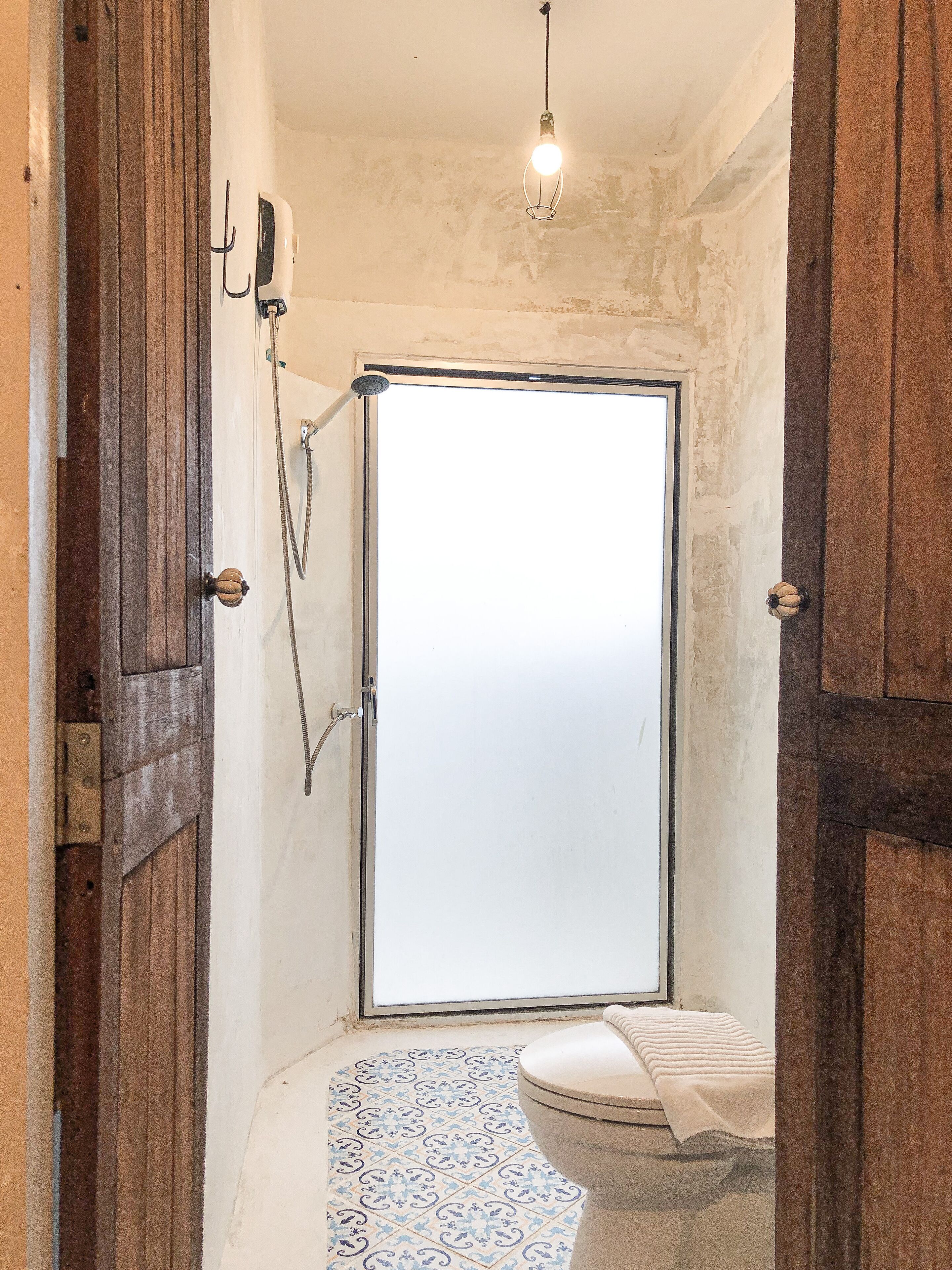 A bathroom with a shower, toilet, and a hanging light fixture.