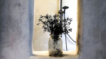 Una ducha con un florero de flores en una ventana.