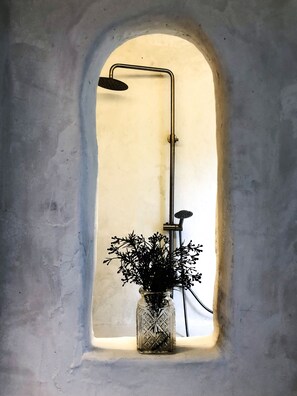 A shower with a glass vase of flowers in a window.