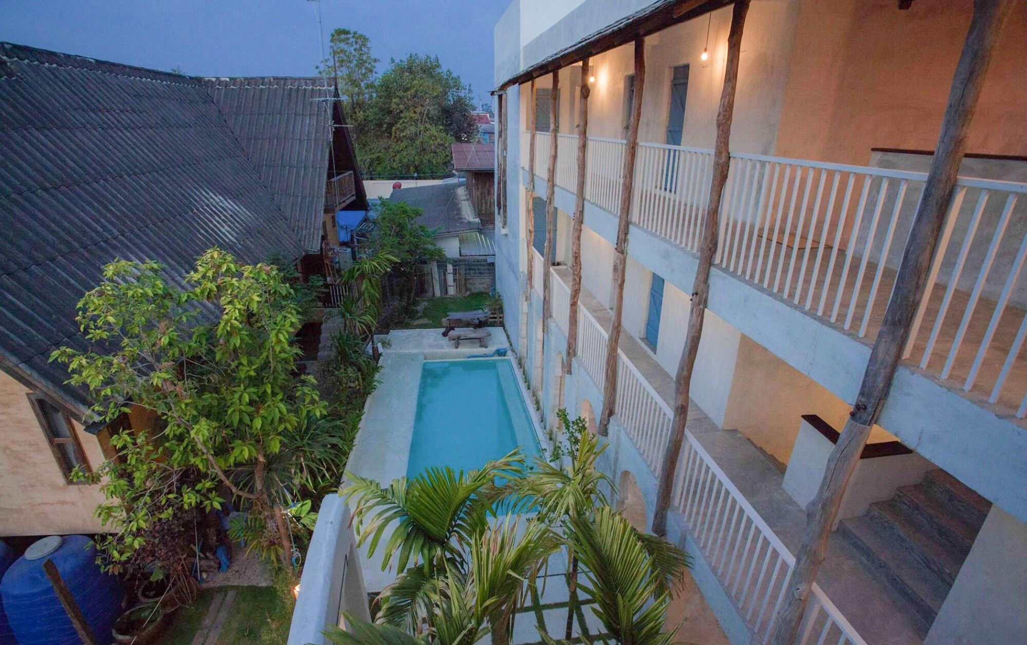 Une cour avec une piscine, entourée d’immeubles dotés de balcons et de rampes en bois.