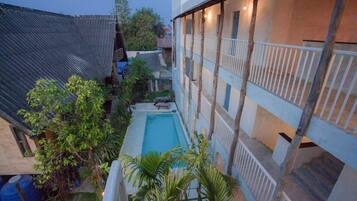 Une cour avec une piscine, entourée d’immeubles dotés de balcons et de rampes en bois.