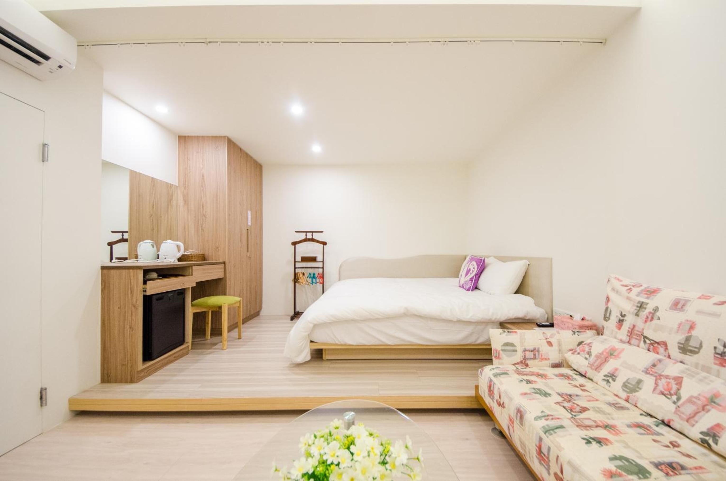 A compact bedroom with a bed, a small desk, a chair, and a sofa.