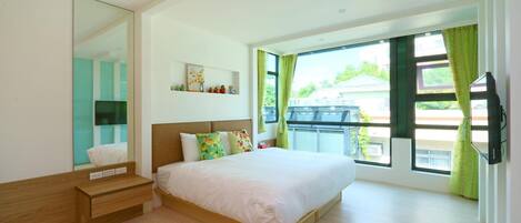 A modern bedroom with a large bed, a bedside table, a mirror, and a window with curtains.