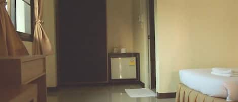A hotel room with a bed, a bedside table, a small cabinet, and a door leading to another room.
