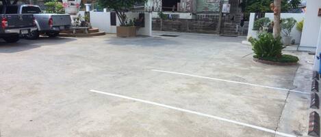 Uma área de estacionamento com piso de concreto, um caminhão e um pequeno edifício com telhado de metal corrugado.