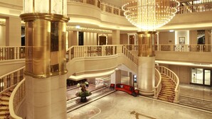 En imponerende hotellobby med en stor lysekrone, flere trapper og en rummelig marmorgulv.
