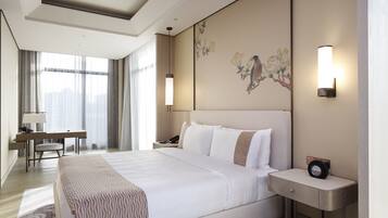 A modern hotel room with a large bed, bedside tables, a desk, and a chair.