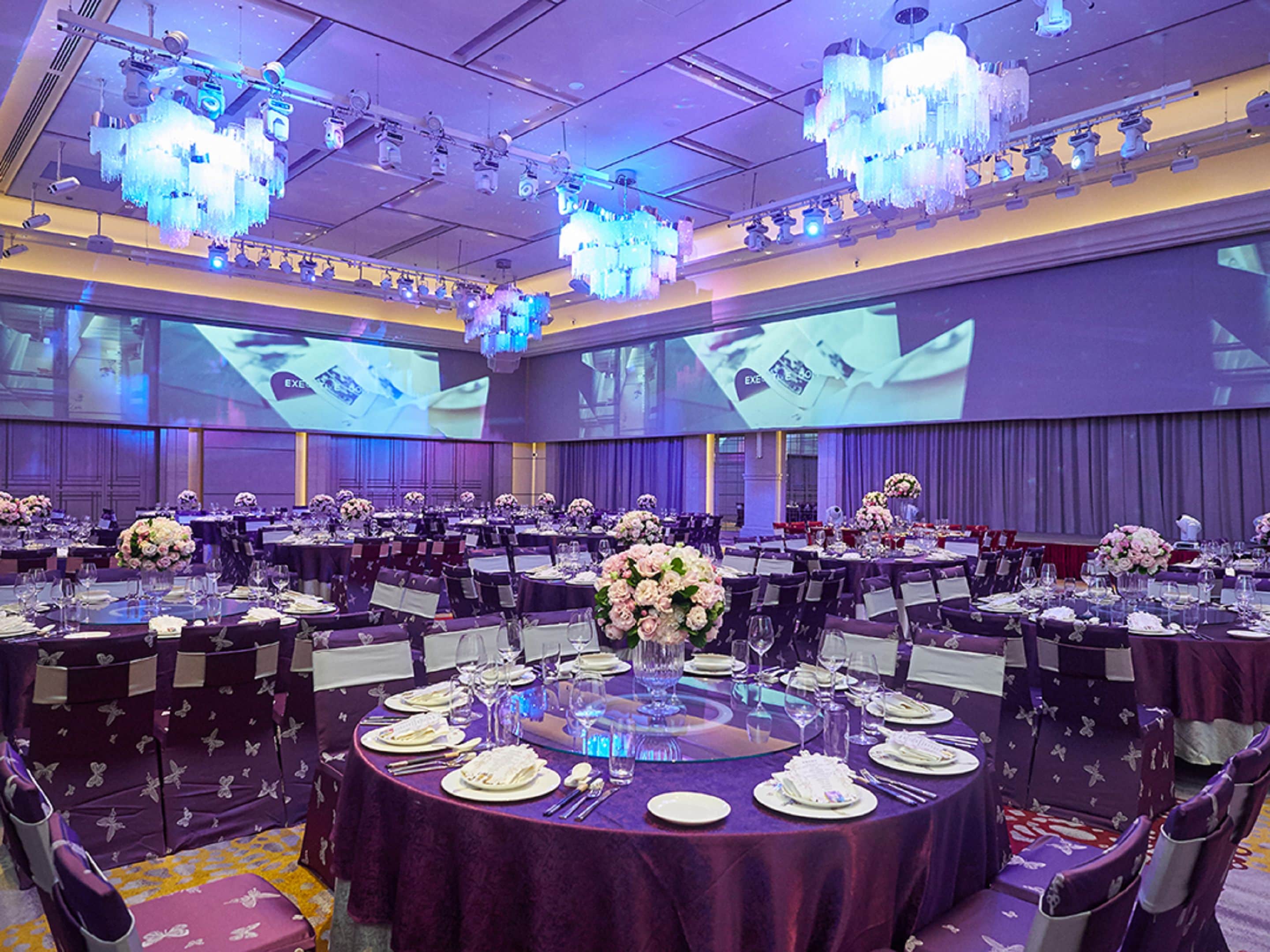 A conference room with round tables, chairs, and floral centerpieces.