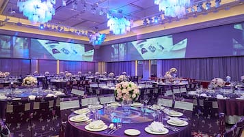 A conference room with round tables, chairs, and floral centerpieces.