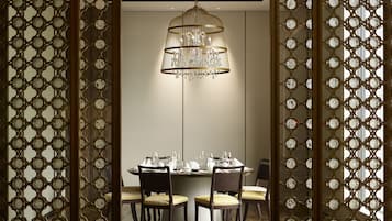 Uma sala de jantar com lustre, mesa redonda e cadeiras.