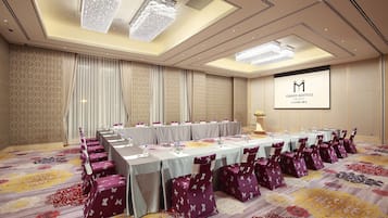 A conference room with a long table, purple chairs, and a chandelier.