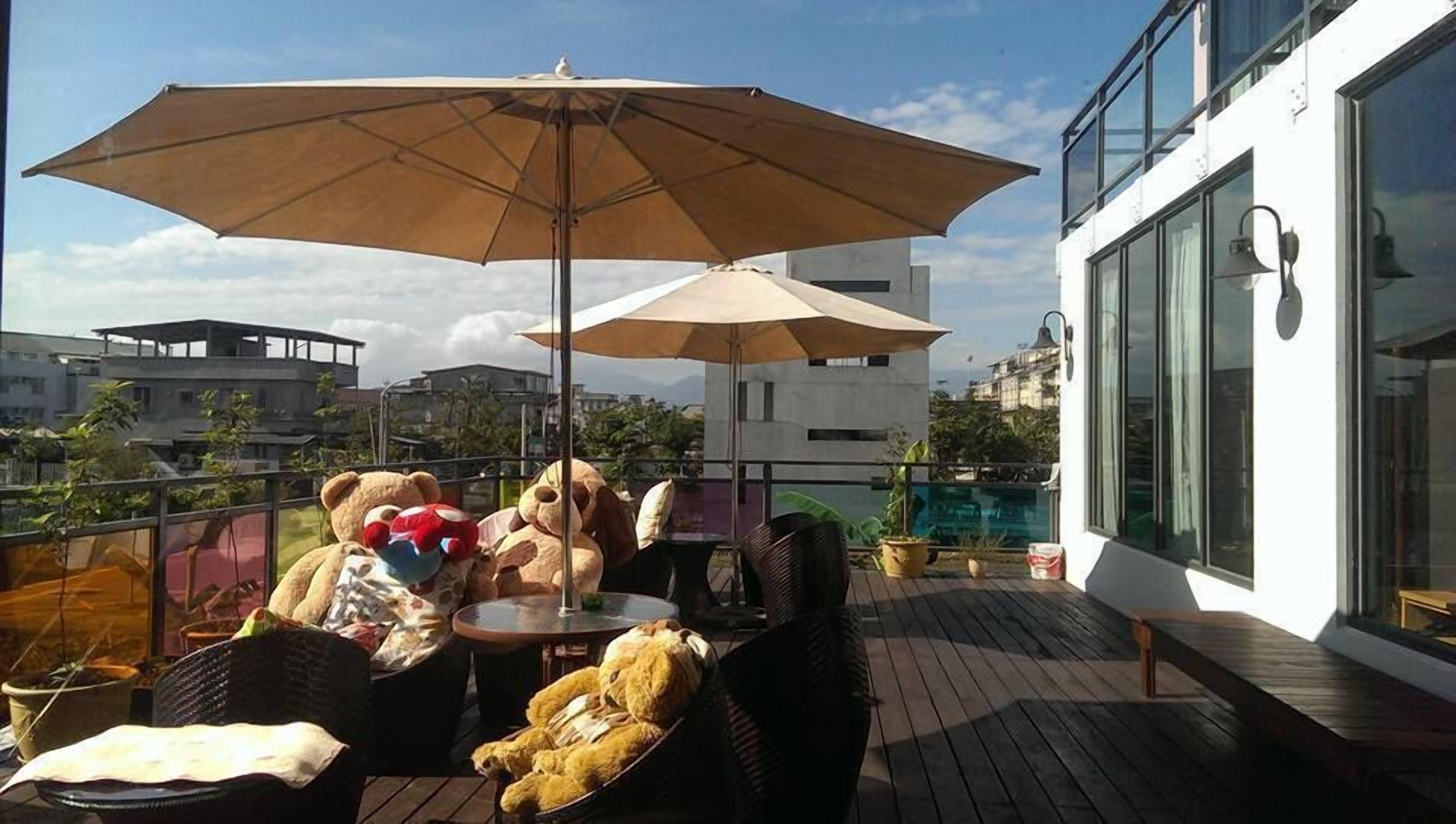 Une terrasse sur le toit, avec une table, des chaises et un grand parasol.