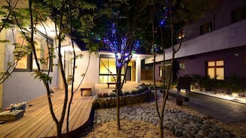 Ein moderner Außenbereich mit Holzterrasse, Steinweg und Bäumen.